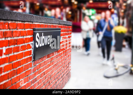 New York City coin de rue avec entrée du métro signe sur mur de briques et de brouiller d'hommes marcher en arrière-plan Banque D'Images