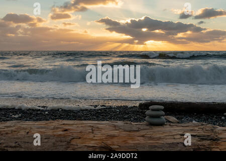 Petit Cairn sur Driftwood avec coucher de soleil sur l'Océan Pacifique Banque D'Images