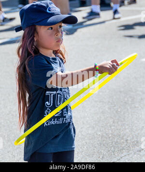 Anaheim, Californie / USA - Nov 3, 2019 : jolie fille, portant une casquette, t-shirt et d'oreilles et avec son visage peint, joue avec un cerceau jaune. Banque D'Images