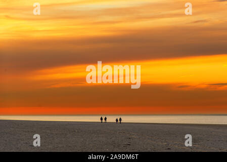 Les poussettes sur la plage de la mer du Nord en face d'un ciel coloré au coucher du soleil Banque D'Images