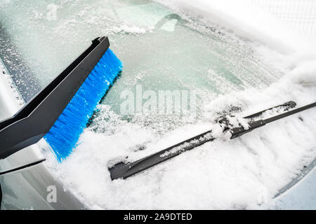Nettoyage de la brosse en plastique bleu de la neige. Pelleter la neige de l'automobile avec chrome plus de détails. Voiture gris à l'extérieur recouvert de neige et de glace. La fenêtre en verre gelé Banque D'Images