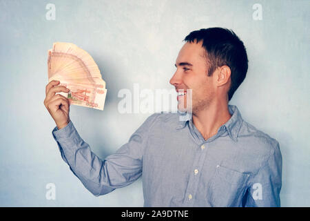 Pile de billets de cinq mille roubles dans la main de l'homme sur fond bleu. Paquet de billets de 5000 roubles de la Fédération de Russie. Banque D'Images