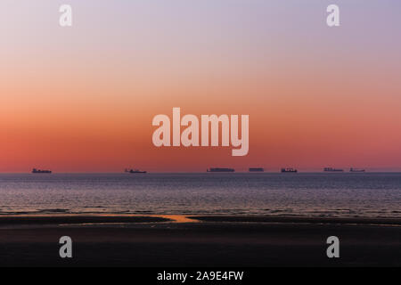 Le soleil se reflète sur la plage de la mer du Nord au coucher du soleil coloré de l'eau de la mer, Banque D'Images