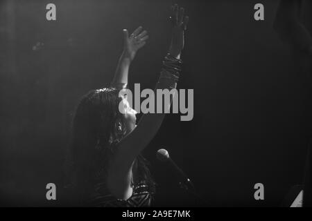 Une femme est vue du musicien un angle faible comme elle chante et joue avec les mains levées et souriant avec public, noir et blanc avec copie espace Banque D'Images