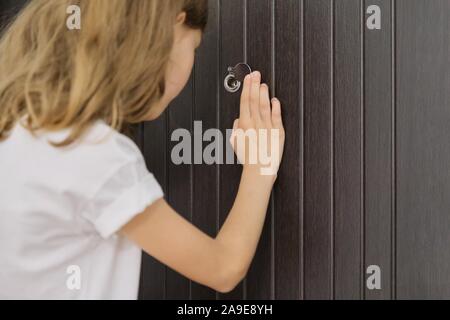 Petite fille à la recherche dans le judas de la porte avant Banque D'Images