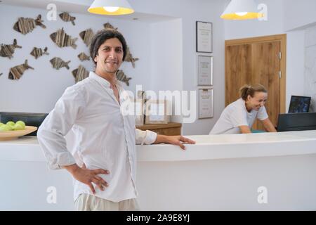 Directeur de l'hôtel, debout près de l'homme/24, femme travaillant à la réception Banque D'Images