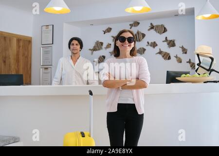 Portrait de femme guest avec valise, homme travailleur près de la réception de l'hôtel Banque D'Images