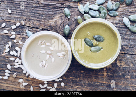Beurre de graines dans des bocaux en verre avec des ingrédients. Des matières tournesol bio et graines de citrouille coller sur table en bois. Vue d'en haut. Banque D'Images