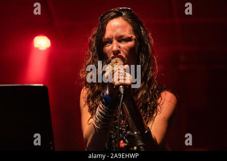 Une femme est vue du musicien un angle faible alors qu'elle chante avec les réactions face au cours d'une performance sur scène avec feux rouges Banque D'Images