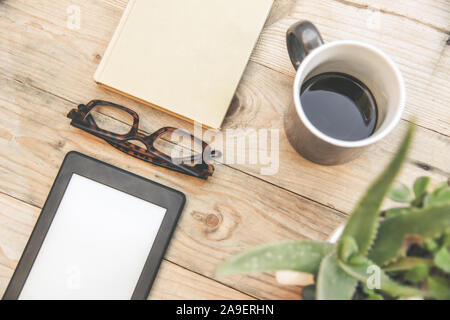 La vie encore Vue de dessus de la nouvelle technologie du livre électronique à côté d'une réserve et les lunettes sur une table en bois et d'un livre vert de l'usine d'aloès. Nouveau périphérique sans fil de haute technologie Banque D'Images