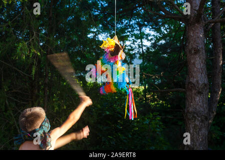 Un garçon aux yeux bandés frapper un pinata avec un bâton Banque D'Images