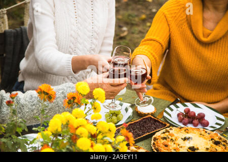 Les femmes d'une famille de plusieurs générations clinks avec des verres à vin pour des vacances en famille l'automne le dîner dans la cour. Banque D'Images