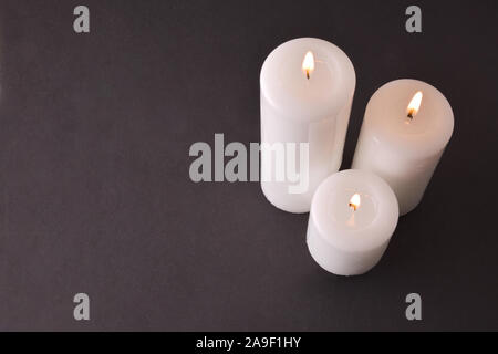 Trois bougies blanches sur fond dégradé de gris. Vue d'en haut. Composition horizontale Banque D'Images