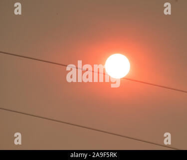 le coucher du soleil dans un ciel orange rose brumeux ressemble à un fil qui s'enroule sur les lignes électriques Banque D'Images