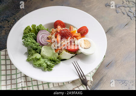 Close-up avec salade de crabe, avocat, des légumes frais et du caviar de saumon sur une plaque blanche. Plan horizontal. Servir sur une serviette à carreaux. Banque D'Images