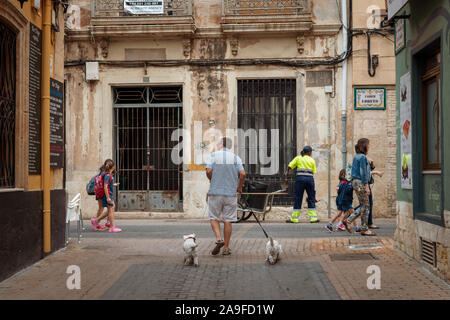 Un homme marche deux chiens le long d'une rue à Denia, Espagne. Banque D'Images