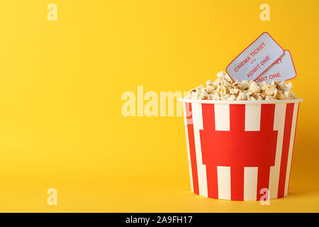 Godet à rayures avec pop-corn et de billets sur fond jaune, copy space Banque D'Images