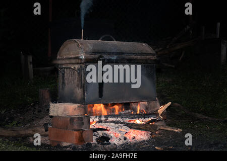 La cuisson des viandes fumées dans un fumoir métalliques mobiles sur le bûcher Banque D'Images