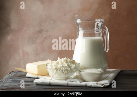 Lait, fromage cottage et de beurre sur table en bois contre fond brun Banque D'Images