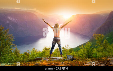 Femme avec bras étendus au coucher du soleil à l'Aurlandsfjord Banque D'Images