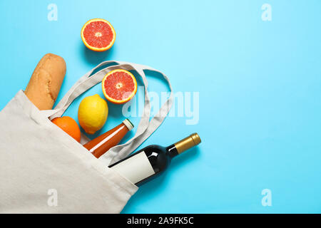 Eco sac avec bouteille de vin, jus, fruits et baguette sur un fond de couleur, de l'espace pour le texte Banque D'Images