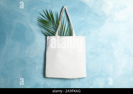 Tote sac de coton avec la feuille de palmier sur mur de couleur, de l'espace pour le texte Banque D'Images