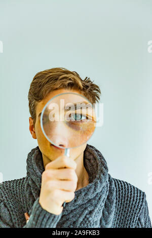 Jeune homme regarde à travers une loupe Banque D'Images