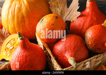 Citrouilles dans panier de paille sur fond de bois, gros plan Banque D'Images