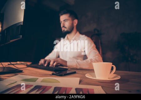 Côté photo de profil ouvrier concentré table sit travailler sur ordinateur finir présentation lire les données statistiques avec double expresso café blanc Banque D'Images