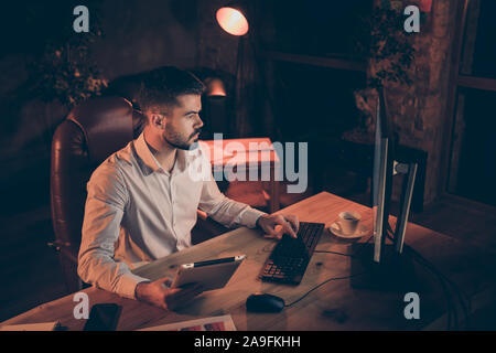 Haut au-dessus de l'angle de vue photo homme pensif grave holding tablet barbu et le calcul sur pc à comparer des données enregistrées sur les deux appareils électroniques Banque D'Images