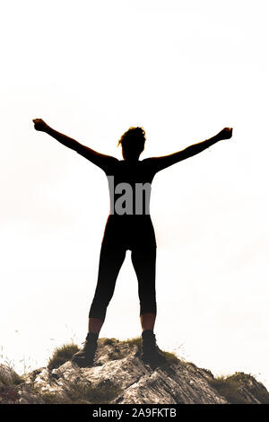 Silhouette féminine dans la région de Victor poser sur un rocher in front of white background Banque D'Images