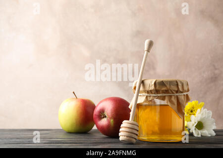 Bocal en verre avec du miel, du balancier, pommes et fleurs sur fond de bois, de l'espace pour le texte Banque D'Images