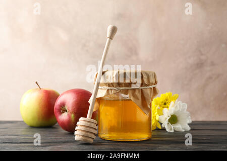 Bocal en verre avec du miel, du balancier, pommes et fleurs sur fond de bois, de l'espace pour le texte Banque D'Images
