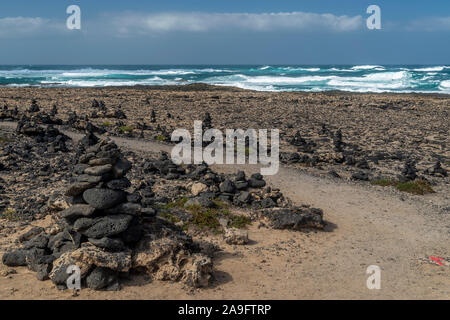 Des piles de cailloux volcaniques le long de la plage de El Cotillo, Fuerteventura, Îles Canaries, Espagne Banque D'Images