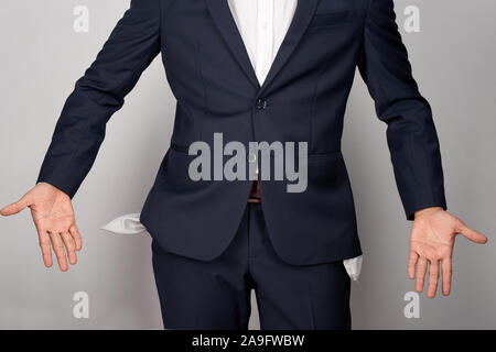 Young businessman showing poches vides, studio shot, isolé sur fond blanc Banque D'Images