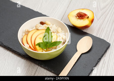 Avec Bol en porcelaine avec de la bouillie de sorgho peach, noix de cajou et amandes, cuillère de bois sur la pierre. Sans gluten vegan salade fraîche avec du sorgho Banque D'Images