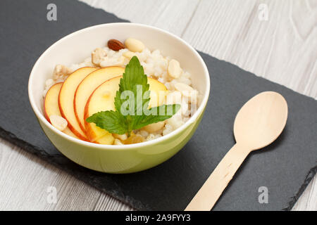 Avec Bol en porcelaine avec de la bouillie de sorgho peach, noix de cajou et amandes, cuillère de bois sur la pierre. Sans gluten vegan salade fraîche avec du sorgho Banque D'Images