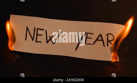 Nouvelle Année mot écrit sur du papier blanc des brûlures. Le feu avec de la fumée et de la cendre sur fond noir Banque D'Images