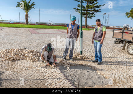 Hommes réparant des pavés portugais traditionnels chemin pavé / route, calcada portuguesa, Olhao Algarve, Portugal. Banque D'Images