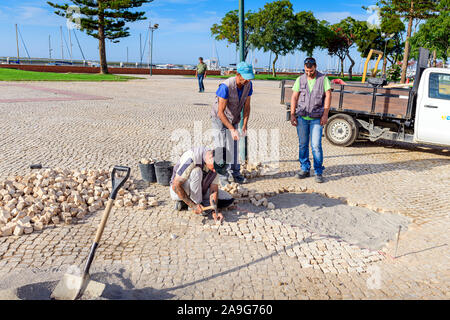 Hommes réparant des pavés portugais traditionnels chemin pavé / route, calcada portuguesa, Olhao Algarve, Portugal. Banque D'Images