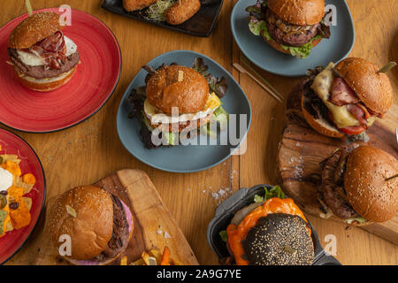 Variété de hamburgers faits maison classique dans le blé et noir avec petits pains hamburgers de veau sur des assiettes en céramique et les planches à découper en bois. Restaurant menu menu. Banque D'Images