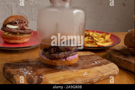 Délicieux petit faim fumé avec plaquettes de bois déchiqueté, Jack Daniel's et de porc BBQ salade américaine sur la base de planche à découper en bois. Banque D'Images