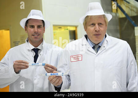 Premier ministre Boris Johnson (à droite) maintenant un peu d'rock, lors d'une visite à la Sucrerie de couronnement à Blackpool tandis que la campagne électorale générale. Banque D'Images