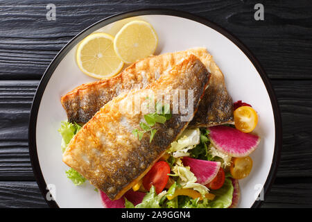 Délicieuse recette de filet de loup de mer grillé épicé avec du citron et salade de légumes sur une assiette sur la table. Haut horizontale Vue de dessus Banque D'Images