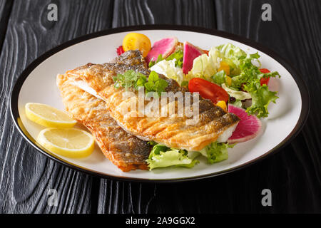 Filet de loup de mer grillé d'or au citron et salade de légumes sains close-up sur une plaque sur la table horizontale. Banque D'Images
