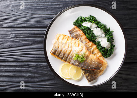 Filet de loup de mer frits servant aux épinards et au citron libre sur une plaque sur la table. haut horizontale Vue de dessus Banque D'Images