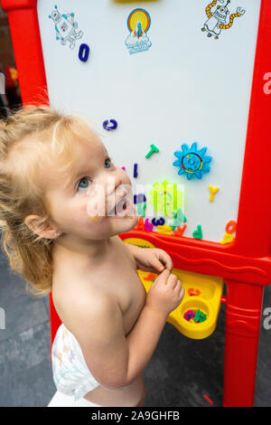 Adorable petit 2 ans préscolaire enfant jouant avec de la craie, lettres arts et artisanat sur son tableau blanc, s'amusant et souriant à l'écart Banque D'Images