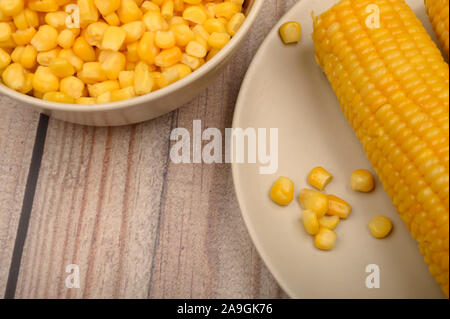 Deux épis de maïs bouillis dans une assiette et un grain de maïs sur la table. Régime alimentaire sain. Régime alimentaire de remise en forme. Pour une petite douceur. Close up Banque D'Images