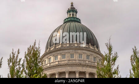 Panorama célèbre bâtiment Utah State Capitol dome encadrées avec des arbres contre ciel nuageux Banque D'Images