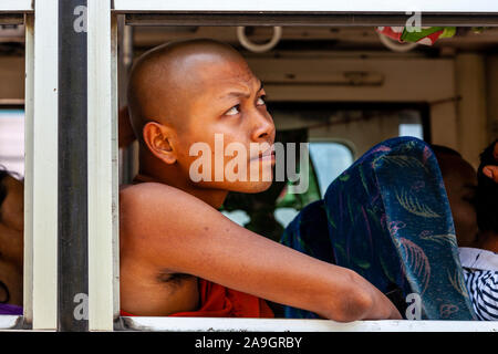 Un moine bouddhiste donne d'une fenêtre de l'autobus, Mandalay, Myanmar. Banque D'Images